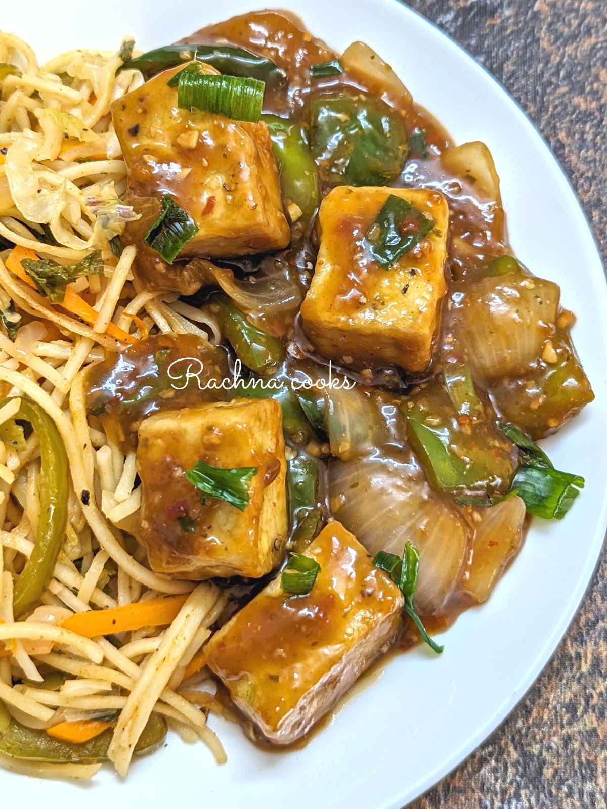 Tofu manchurian served with noodles on a white plate.