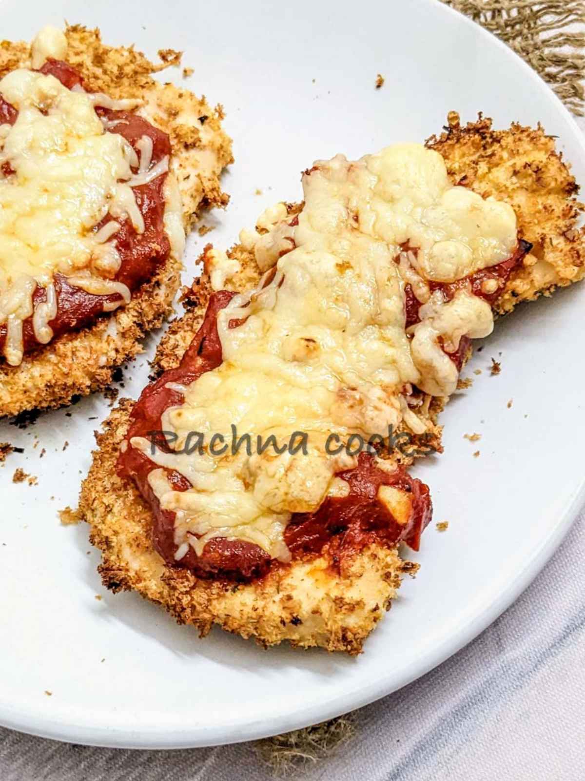 1 chicken parmesan in focus served on a white plate.
