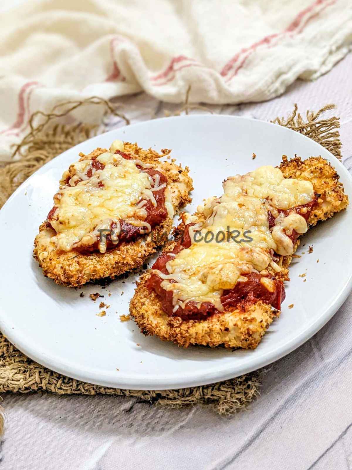 2 chicken parmesan served on a white plate.