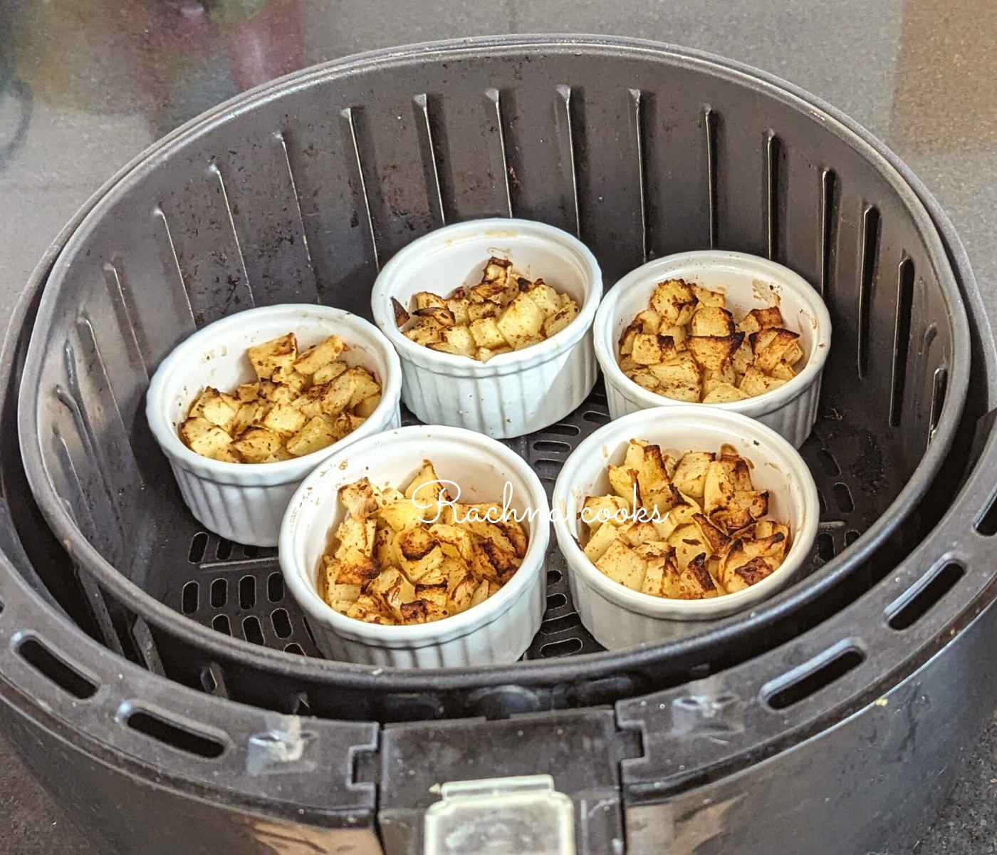Caramelized and cooked apples in ramekins in air fryer basket