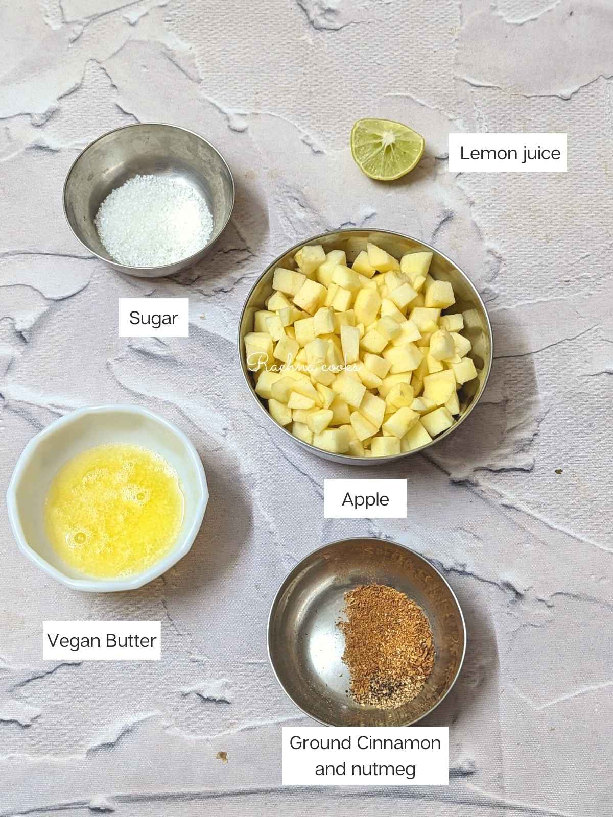 Cubed apple, vegan butter, cinnamon and nutmeg, sugar, brown sugar and lemon juice in bowls