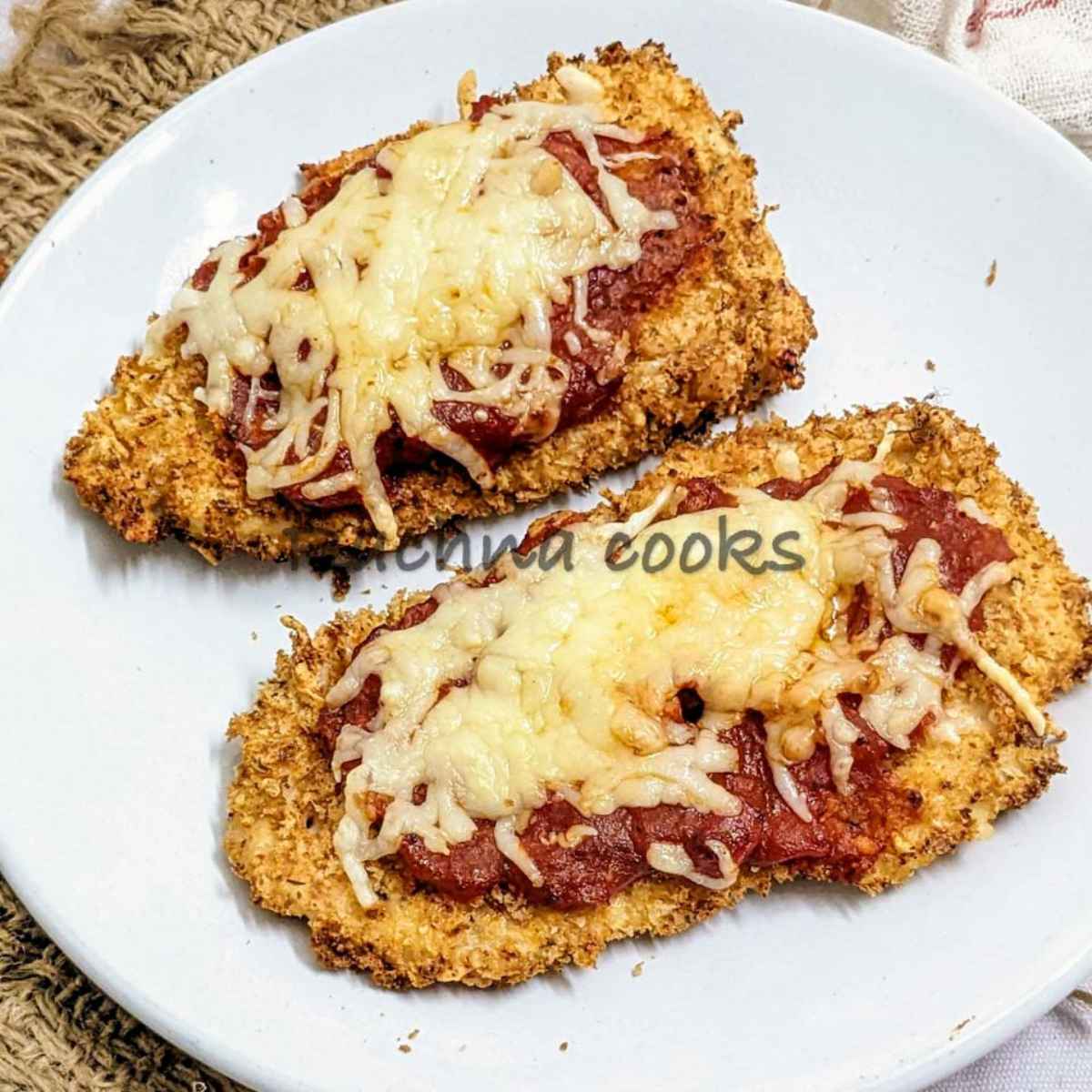 Chicken parmesan served on a white plate.