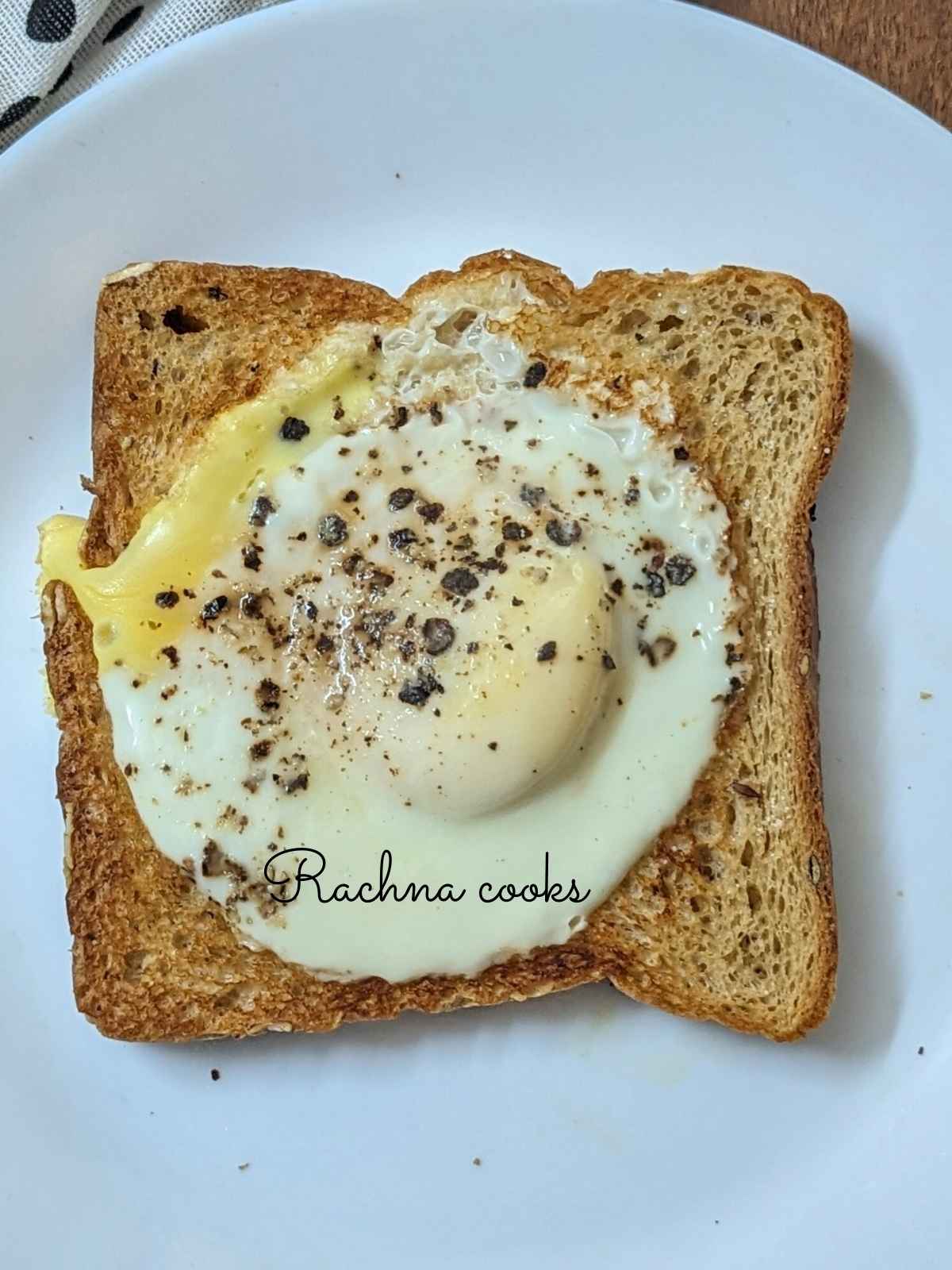 Runny egg yolk and well set white in a bread slice for egg toast.