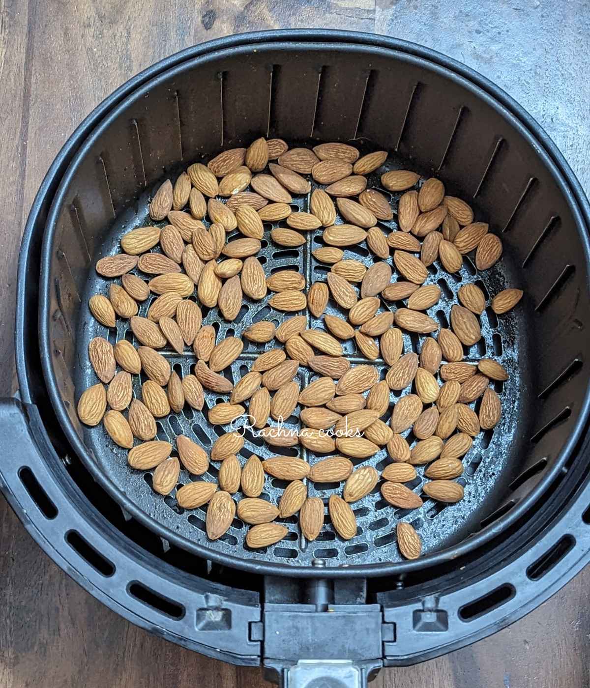 1 cup of almonds laid out in air fryer basket.