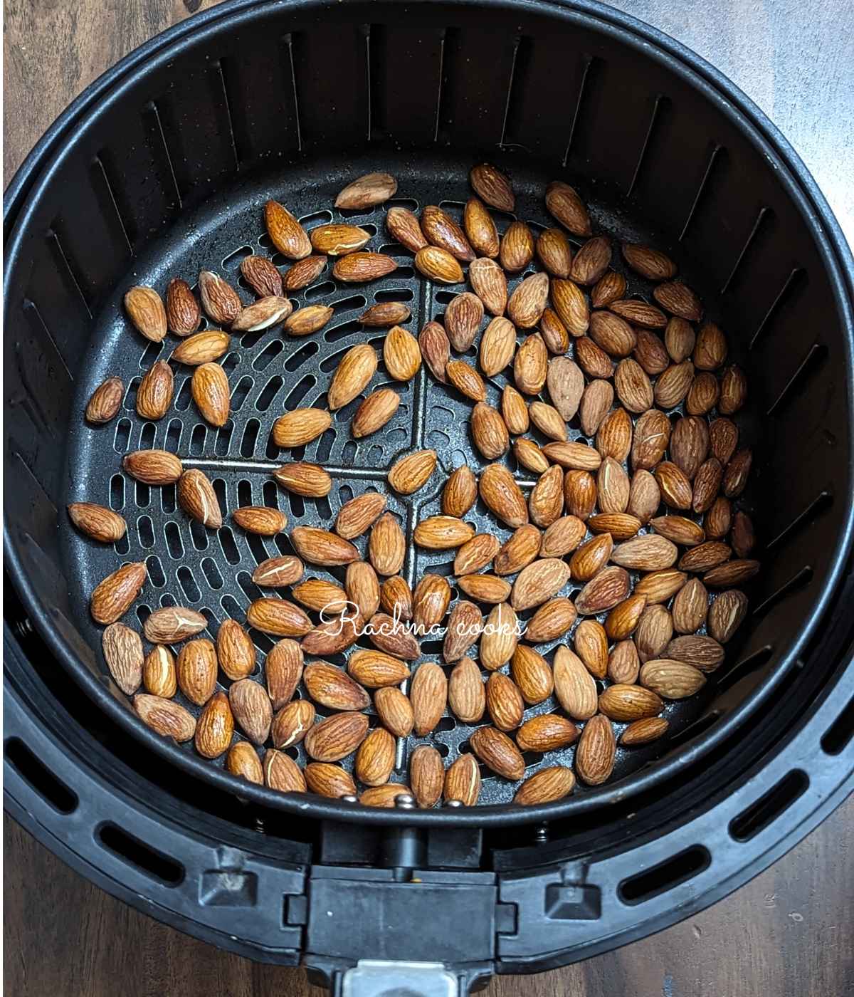 Roasted almonds after air frying in air fryer basket.