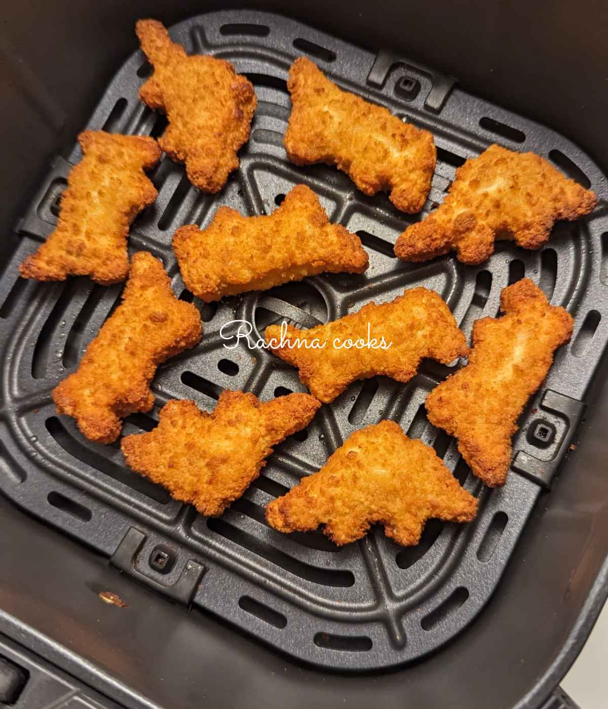 Crunchy golden dino nuggets in air fryer basket after air frying.