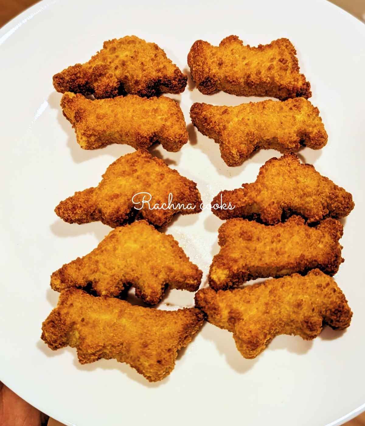 Dino nuggets after air frying served on a white plate.