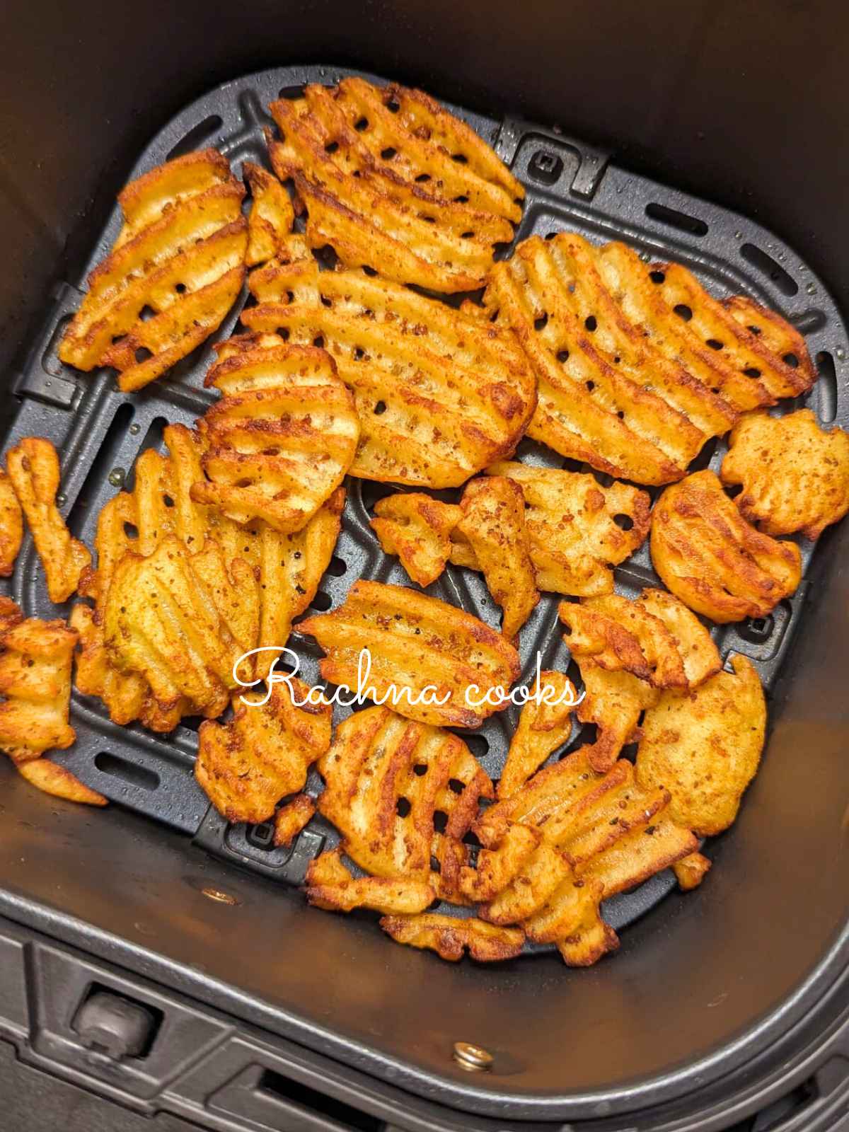 Golden waffle fries after air frying in air fryer basket.
