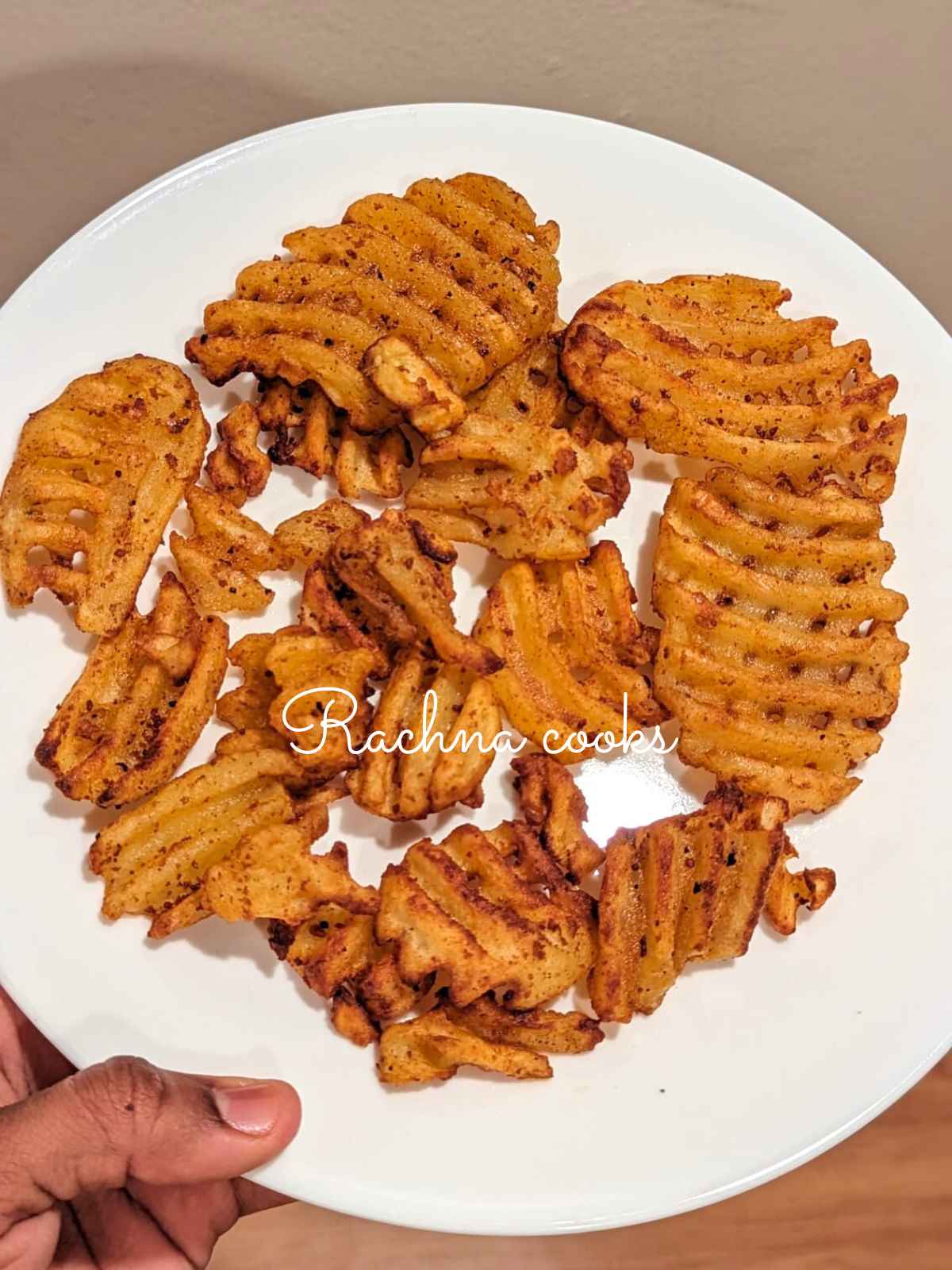 Golden waffle fries after air frying served on a white plate.