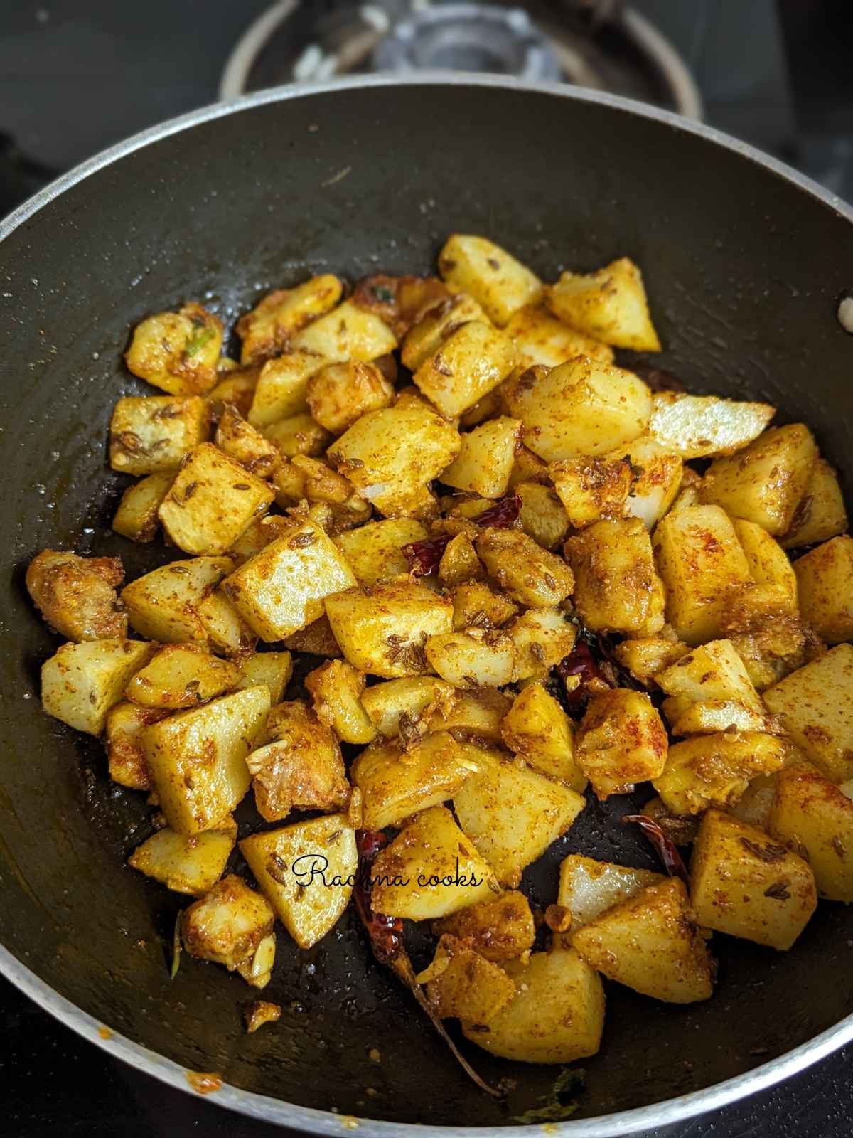 Potatoes with red chilli powder and salt added to kadhai.