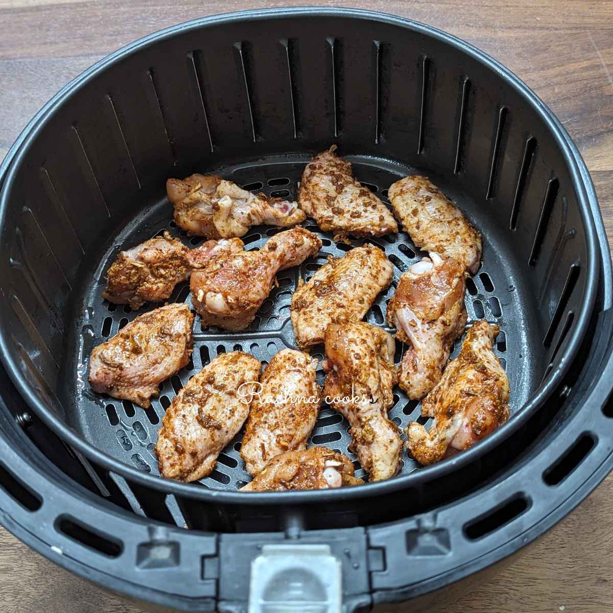 Marinated chicken wings placed in air fryer basket.