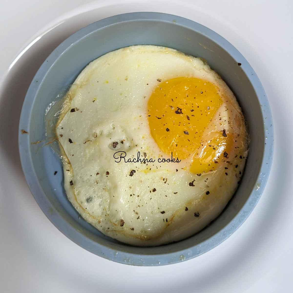 1 silicone cup with fried egg topped with salt and pepper