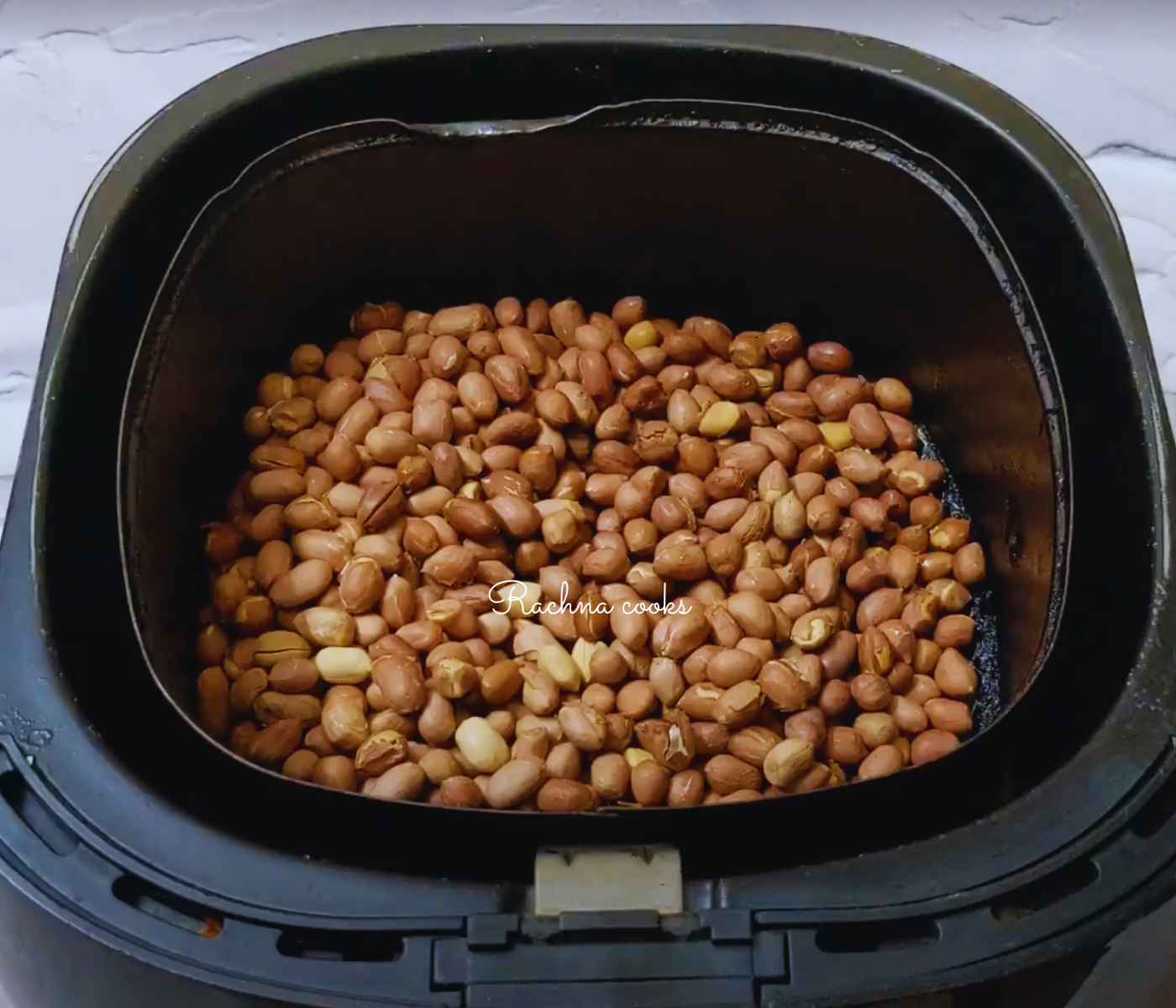 Browned peanuts after air frying in air fryer basket.