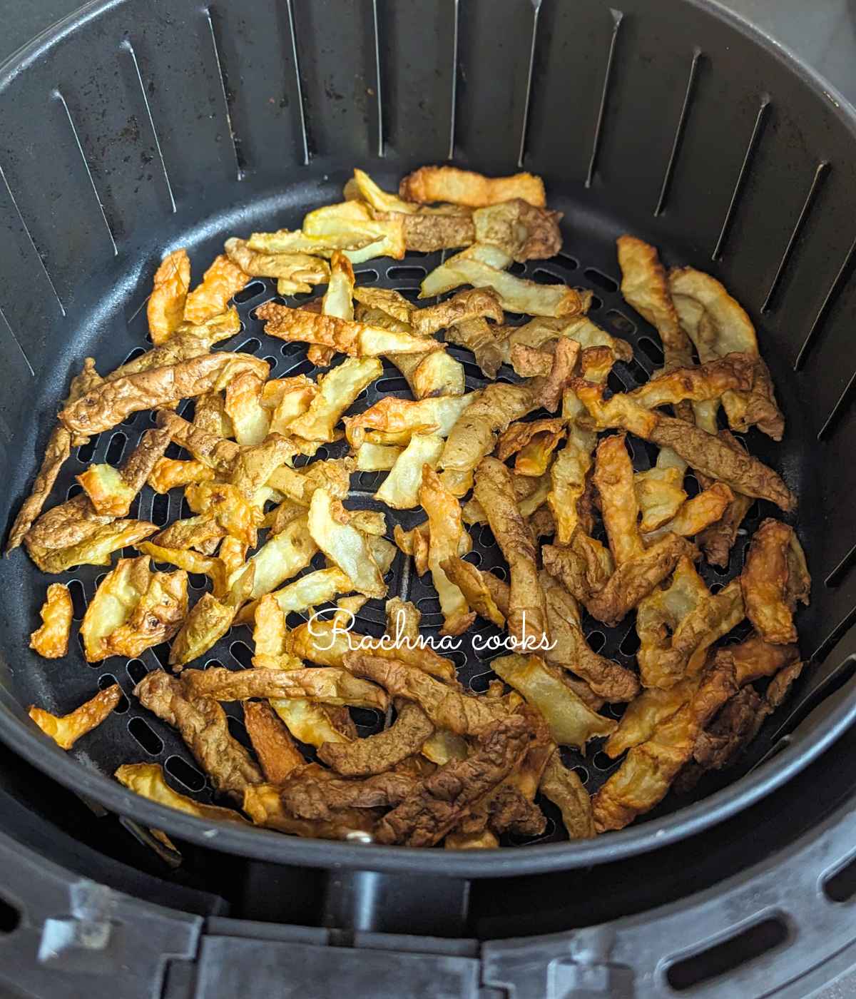 Crispy air fryer potato peels in air fryer basket after air frying.