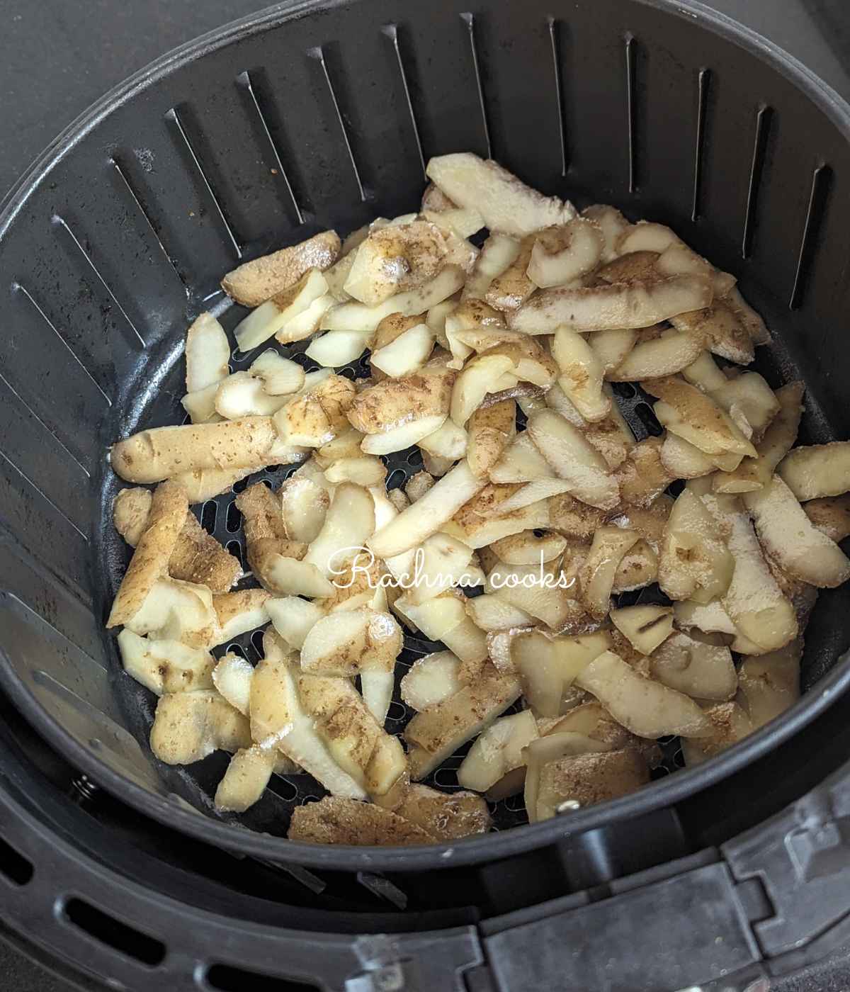 Seasoned potato peels placed in air fryer basket.