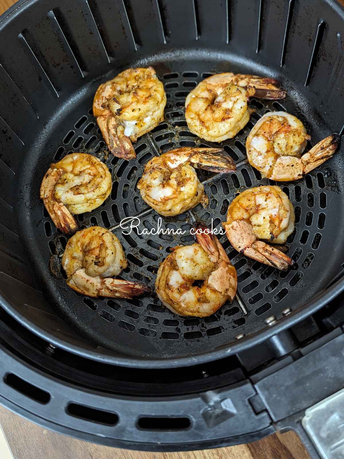 Shrimp after air frying in air fryer basket.