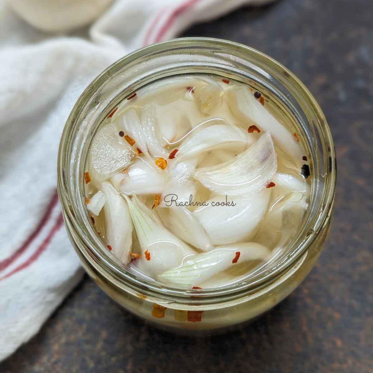 Top shot of pickled white onions in a glass jar.