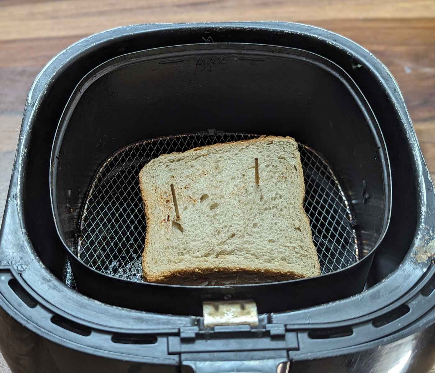 Sandwich placed in air fryer basket.