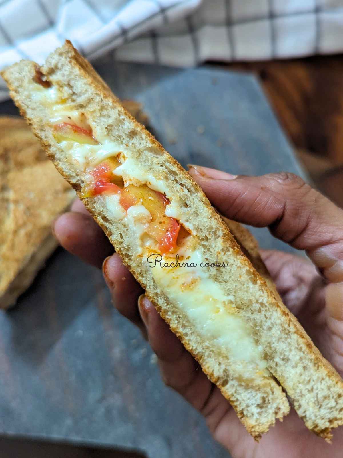 Half of tomato cheese melt sandwich held up in hand.