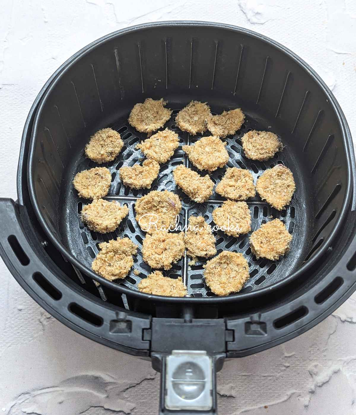 Breaded onion petals placed in air fryer basket.