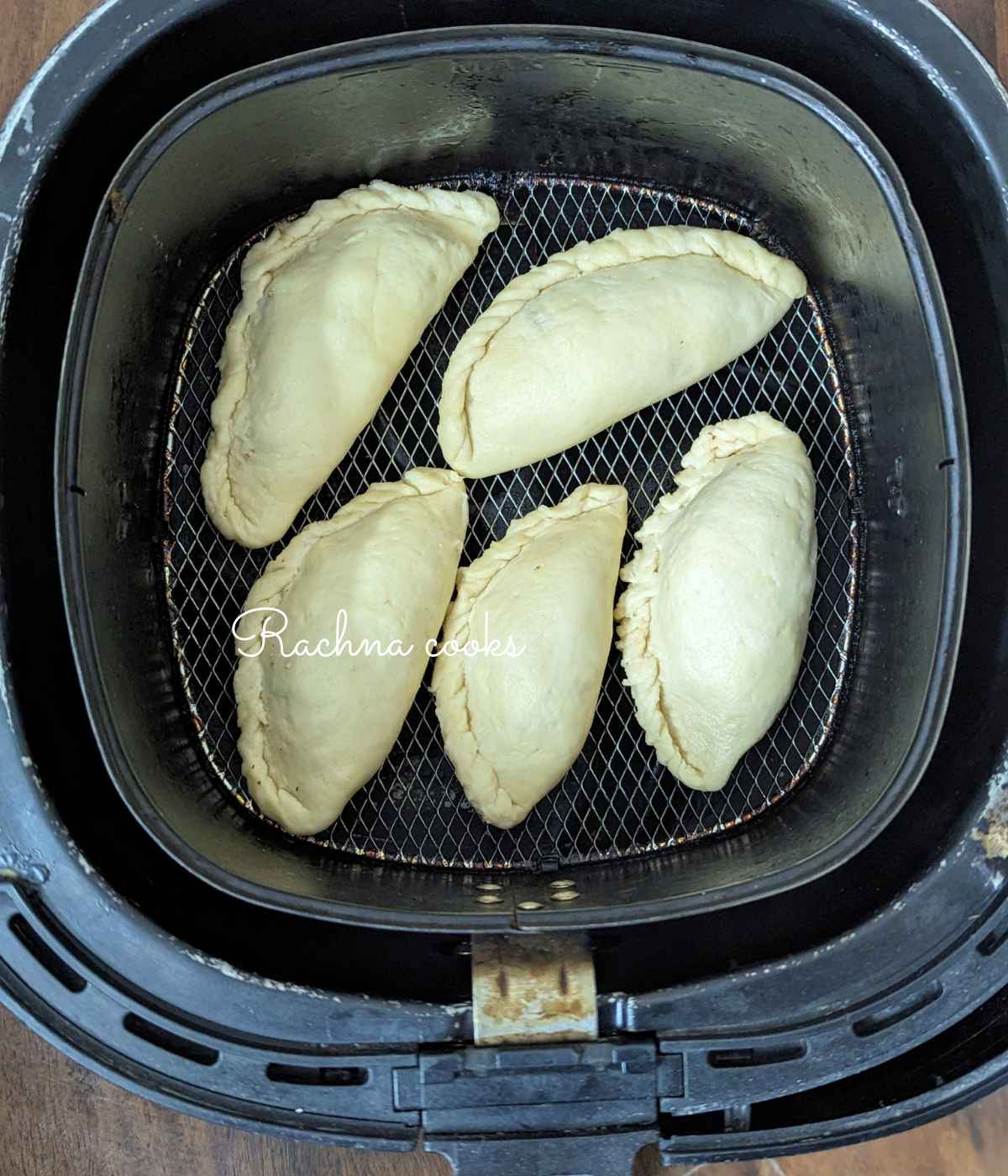 5 gujiyas placed in air fryer basket.