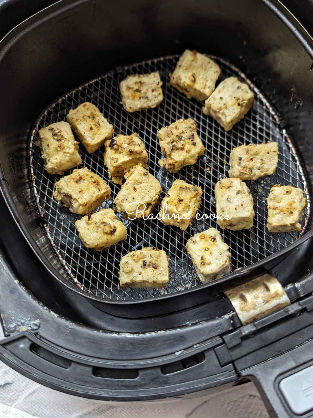 Air fried golden tofu cubes in air fryer basket.
