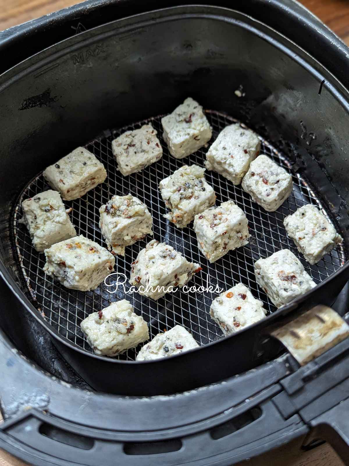 Seasoned tofu cubes in air fryer basket.