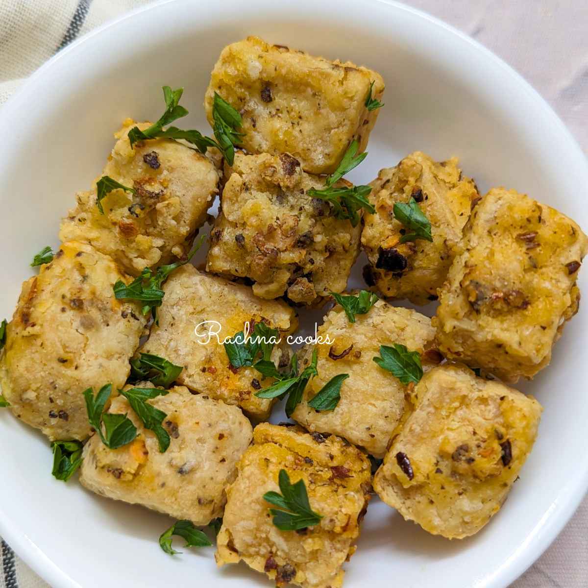 Air fried salt and pepper tofu cubes served in a white bowl.