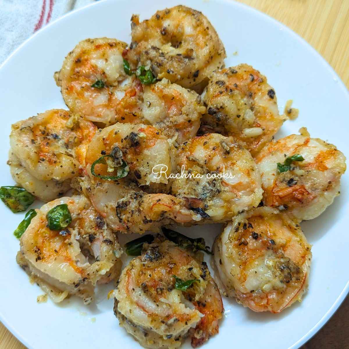 salt and pepper shrimp in air fryer served on a white plate.