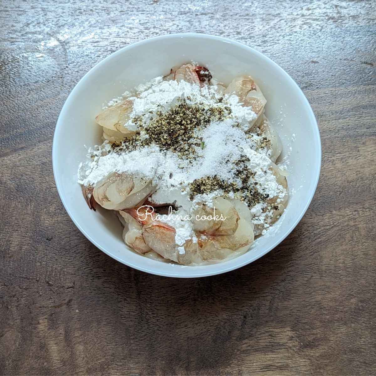 Shrimp in a bowl with cornstarch, pepper, salt .