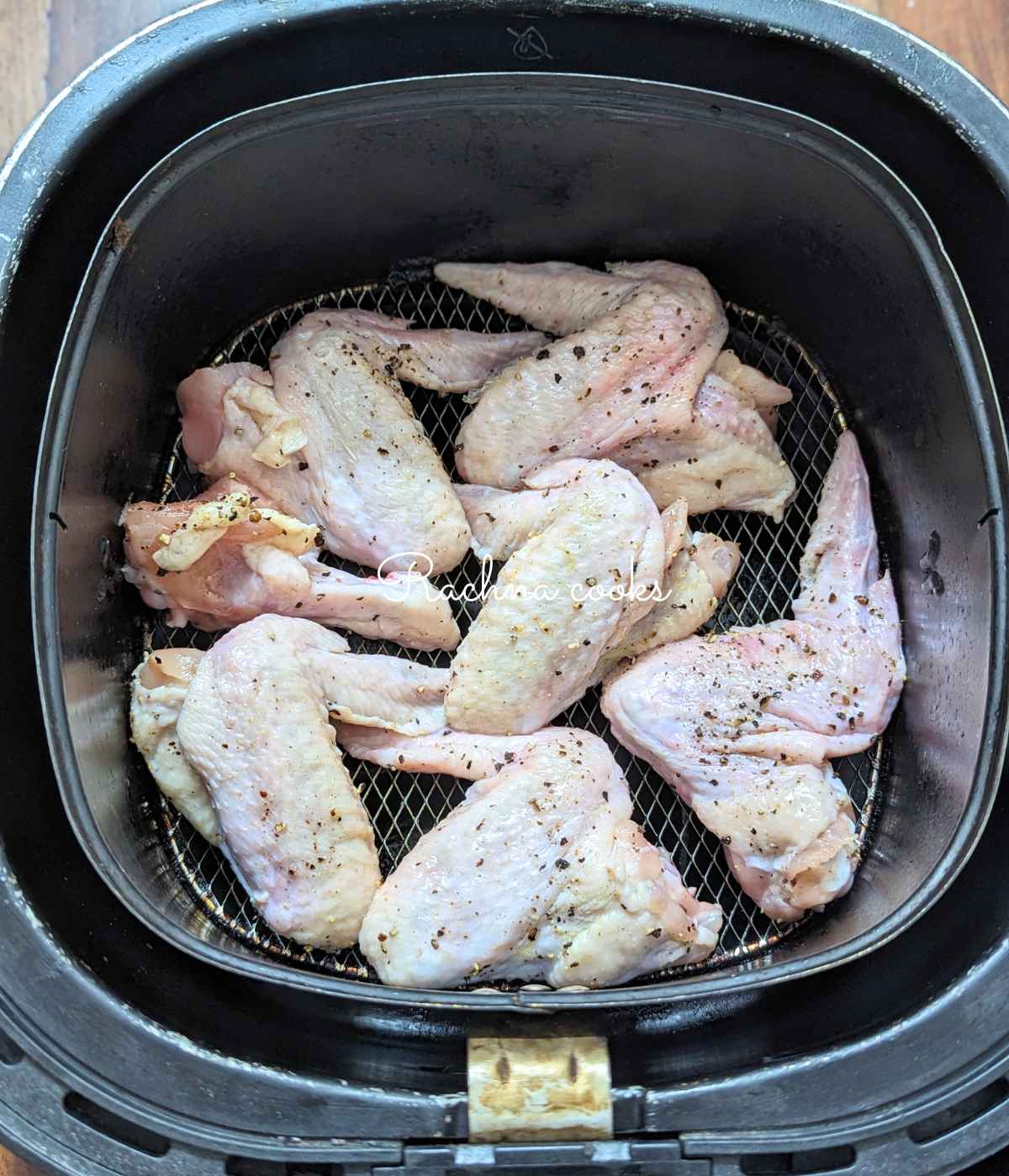 Seasoned chicken wings placed in iar fryer basket ready for air frying.