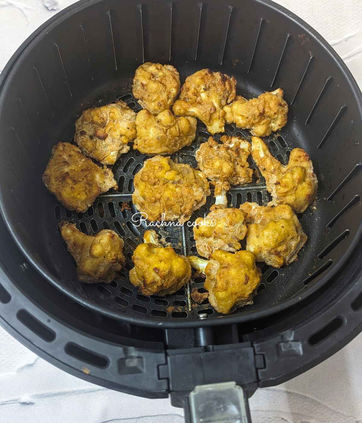 Half cooked cauliflower florets brushed with oil and placed back in the basket.