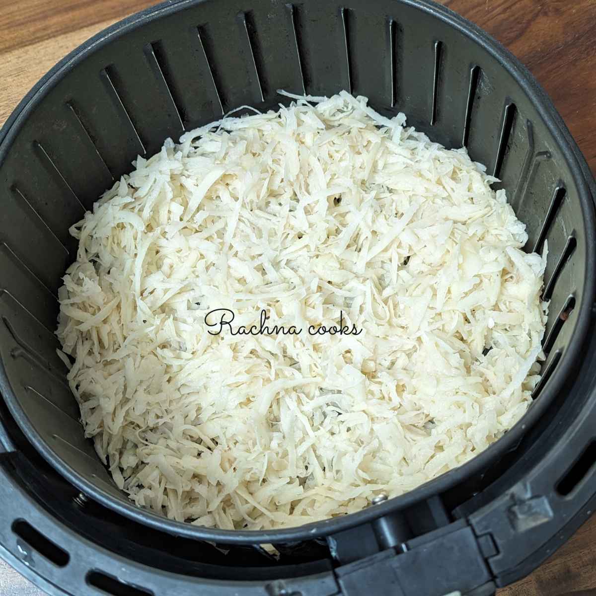 Shredded seasoned hash browns in air fryer basket