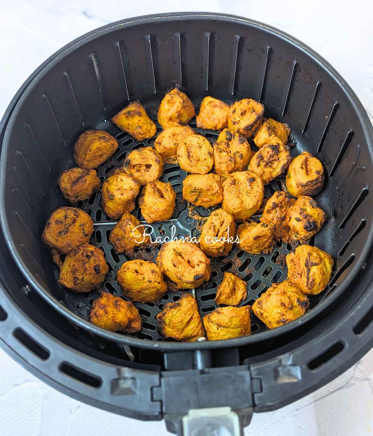 Browned and delicious tandoori soya chaap after air frying in air fryer basket.