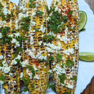 Mexican corn on the cob served on a white plate