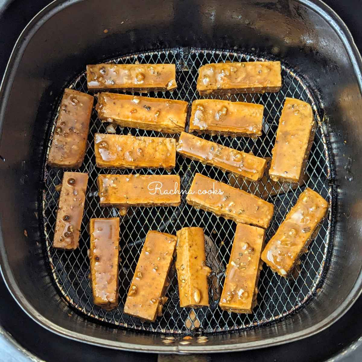 Marinated tofu fries in air fryer basket for air frying