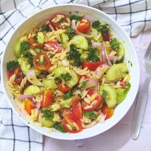 Delicious orzo veggie salad in a white bowl