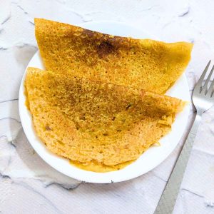 Two red lentil pancakes served on a white plate