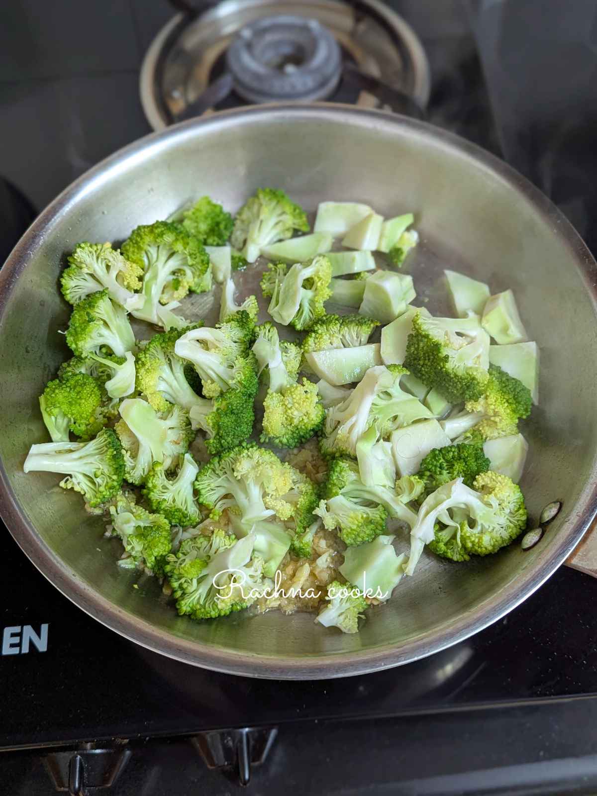 Broccoli being stir fried with ginger and garlic in a pan