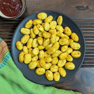 Air fried gnocchi on plate served with ketchup on the side.