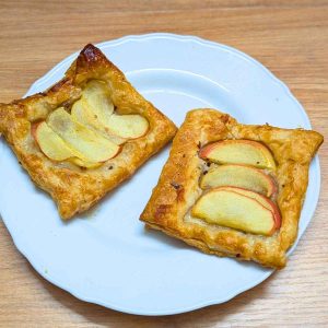 Two upside down apple tarts with puff pastry on a plate