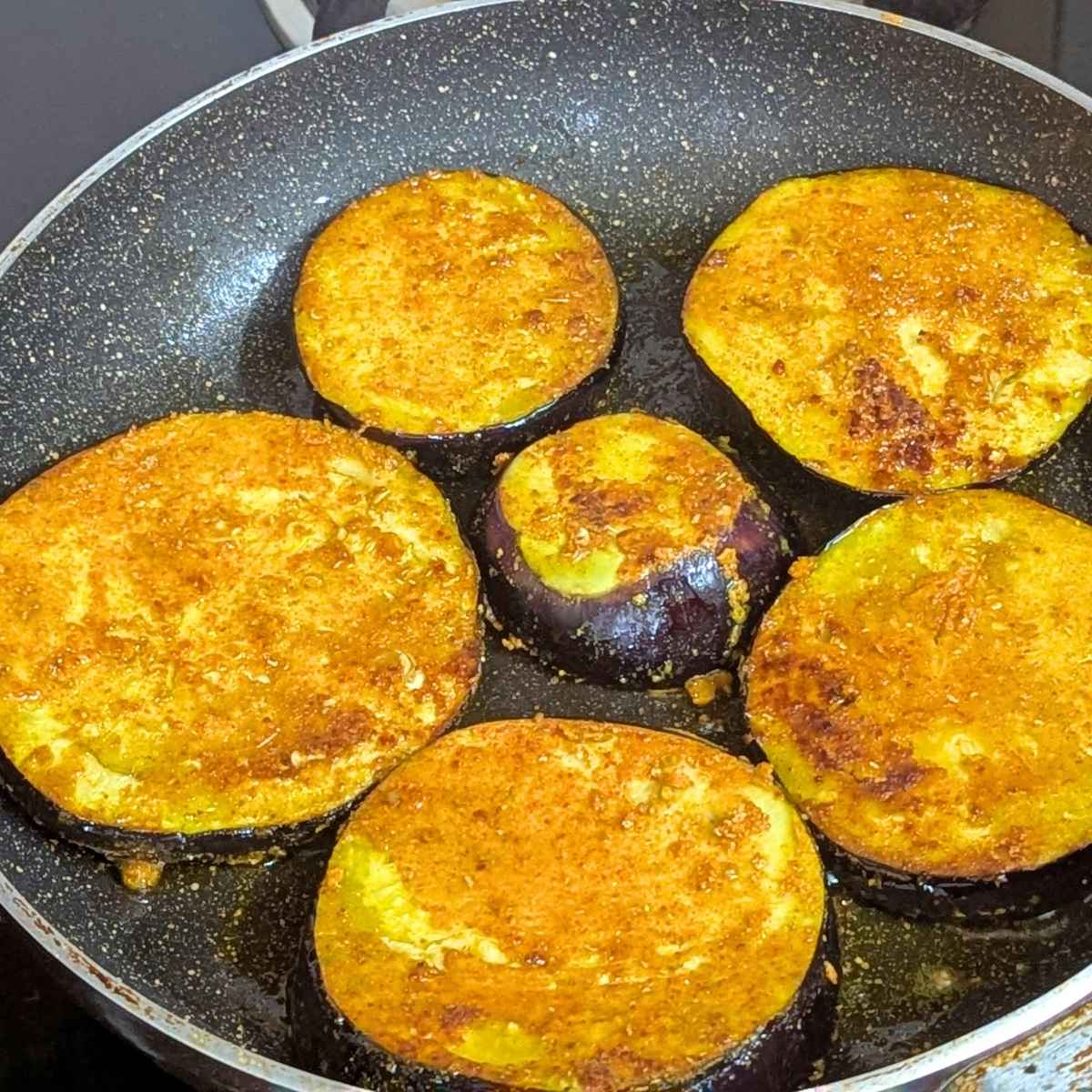 seasoned eggplant slices for shallow frying in pan.