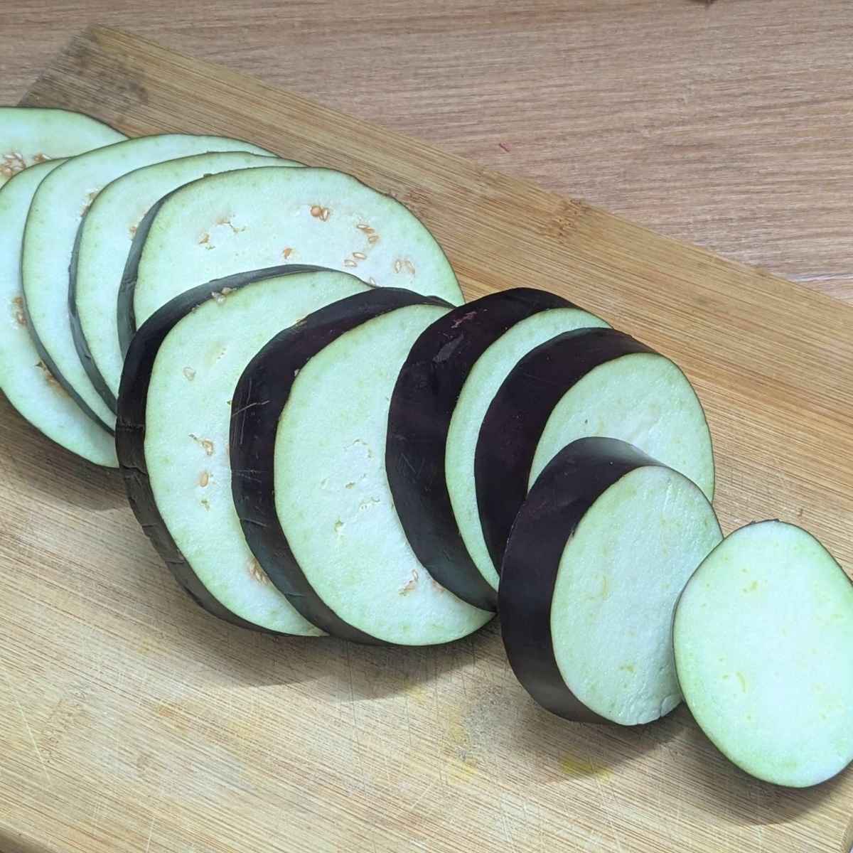 Eggplant cut into ¼ inch slices on chopping board