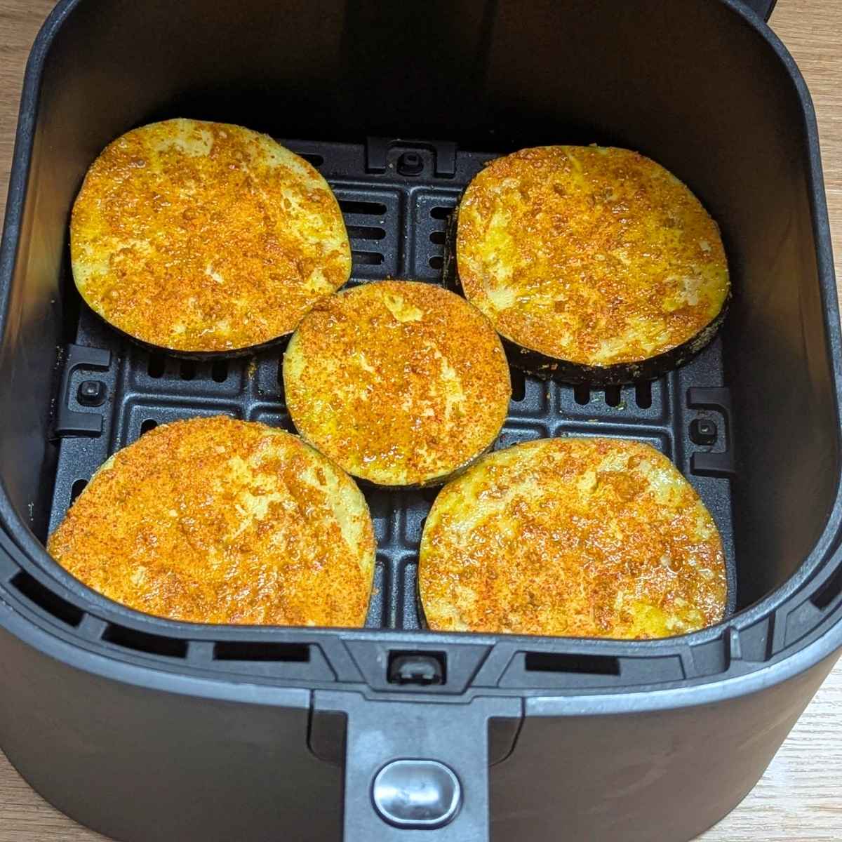 Seasoned eggplant slices in air fryer basket