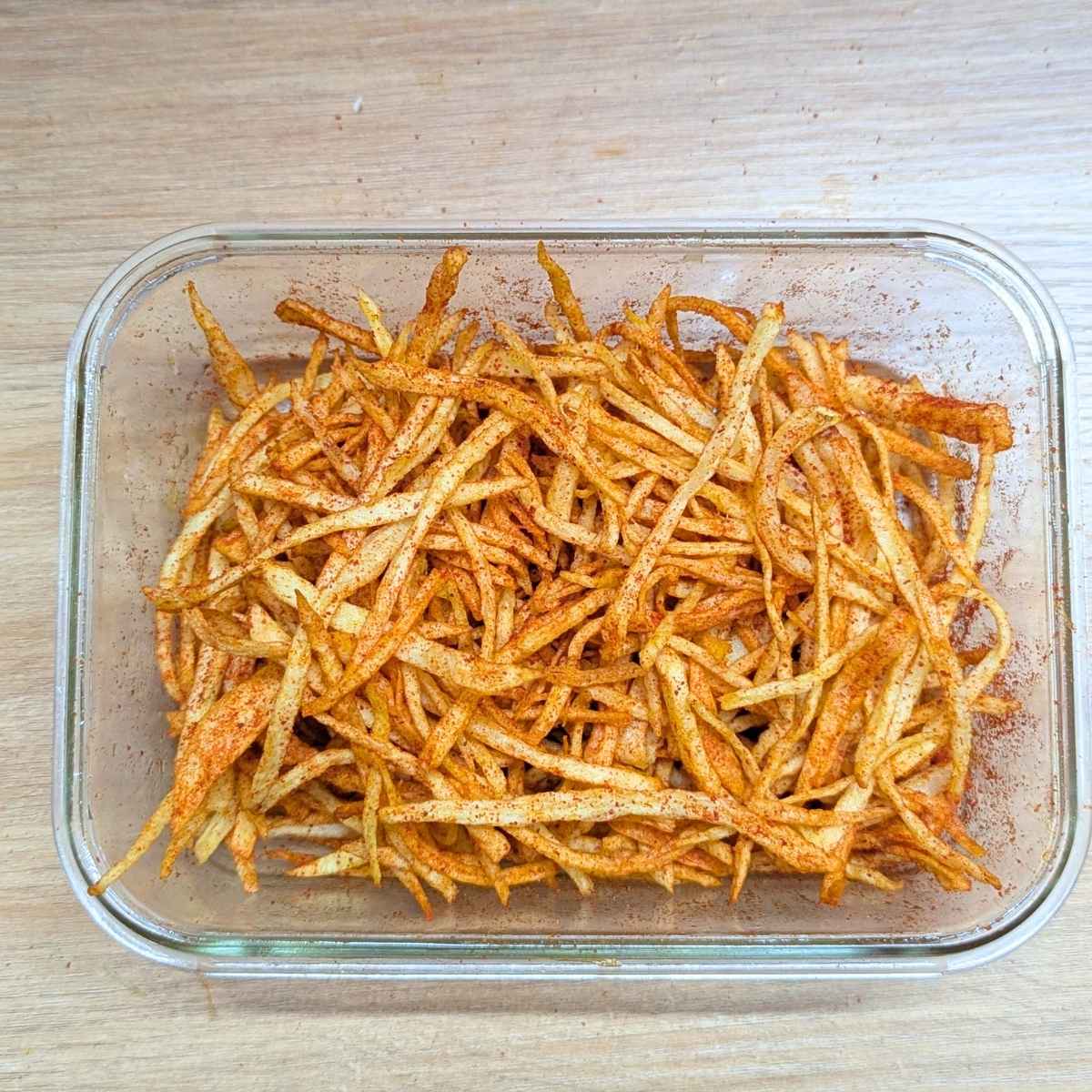 Shoestring fries in a bowl after tossing with seasonings