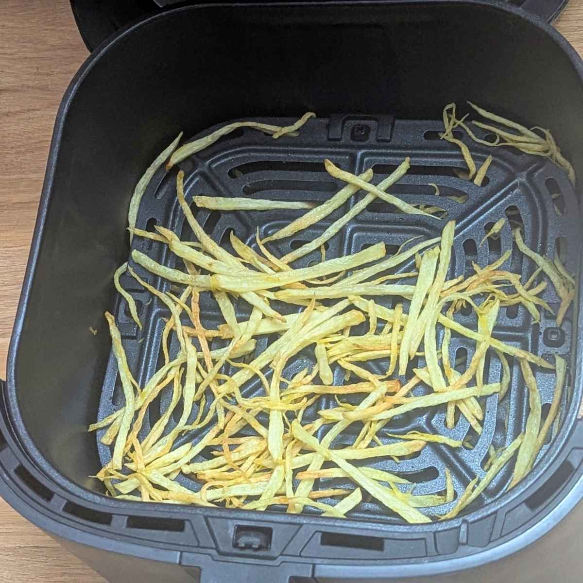 Shoestring fries in air fryer basket after air frying.