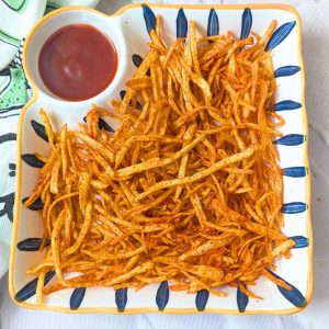 Shoestring fries served in a plate with ketchup