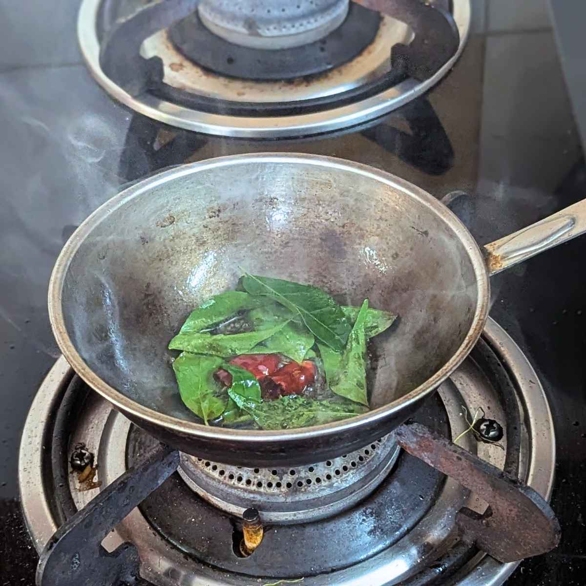 Tempering of curry leaves, mustard seeds and dry red chilli in oil.