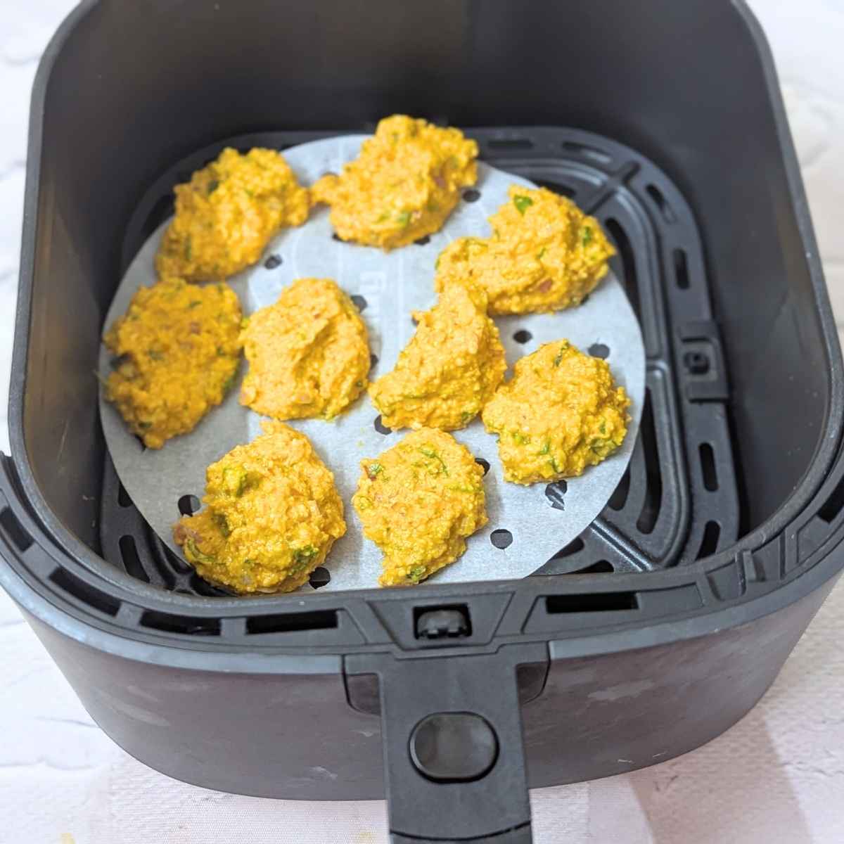Moong dal pakora laid our in air fryer for air frying.