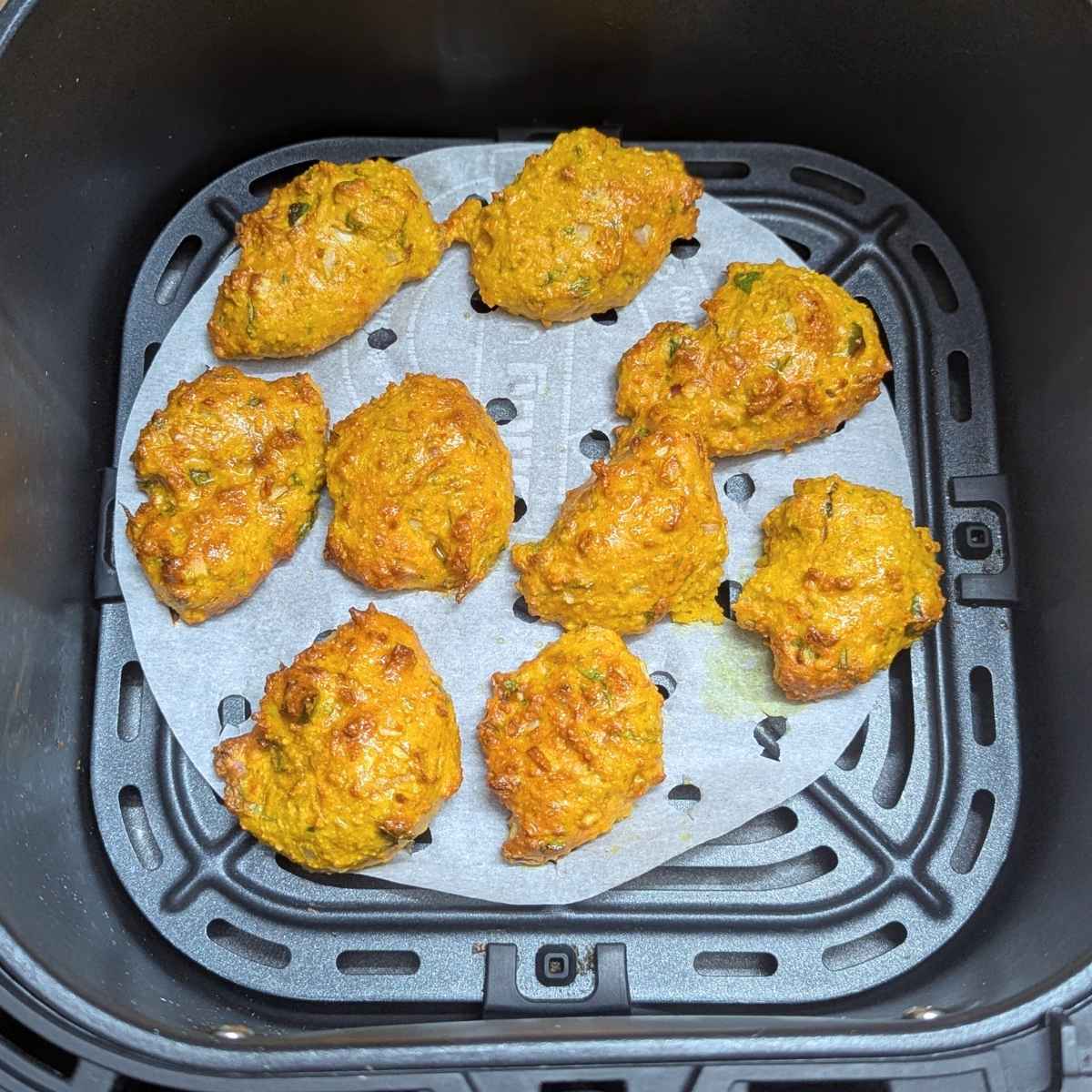 Moong dal pakora after air frying in air fryer basket.